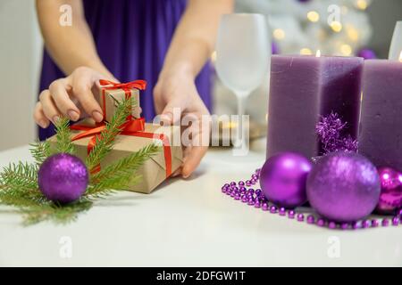 Mädchen macht Weihnachten Tischdekoration mit Geschenken und lila Kerzen. Hohe Qualität Stockfoto