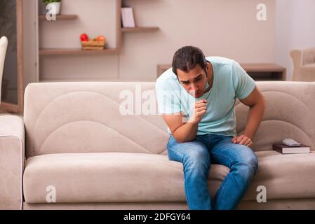 Junger Mann Student Husten zu Hause während Pandemie Stockfoto