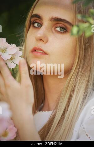 Glücklich ziemlich blonde Mädchen mit Blumen Blick auf die Kamera Stockfoto