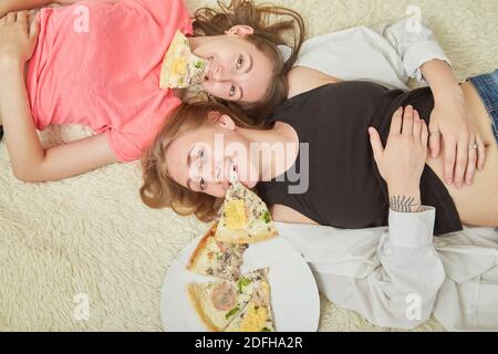 Überessen Mädchen Lügen mit Pizza Stücke im Mund Stockfoto