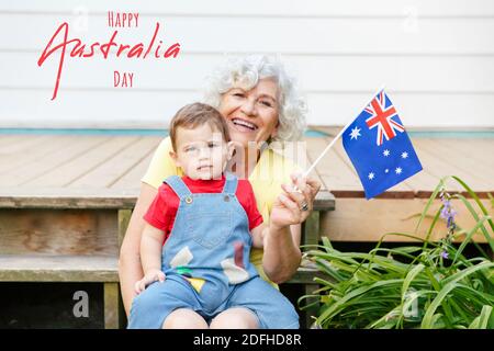 Happy Australia Day Karte mit Grußtext. Glückliche alte Frau Großmutter mit Enkel Baby Junge winken australische Flagge. Familienbürger feiern Au Stockfoto