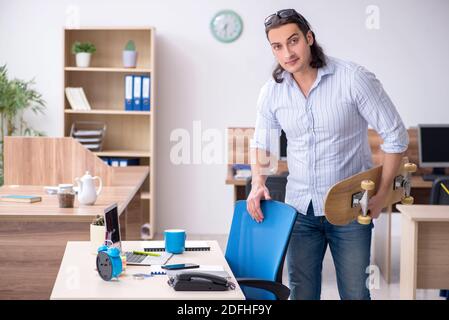 Junge Mitarbeiterin mit Skateboard im Büro Stockfoto