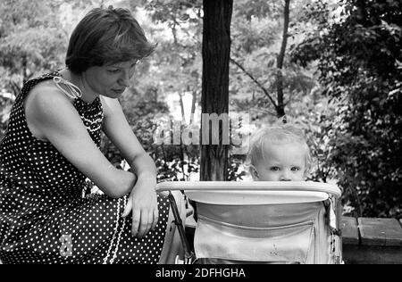 Schwarz-Weiß-Foto von jungen kaukasischen Frau mit einem Jungen, der in einem Rollstuhl sitzt, UdSSR Stockfoto