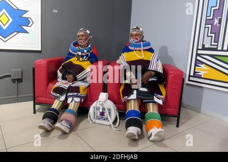 Johannesburg, Südafrika. November 2020. Traditionell gekleidet sitzen die südafrikanische Künstlerin Esther Mahlangu (l.) und ein Verwandter in einer Galerie, in der Mahlangs Arbeiten ausgestellt sind. Der 85-jährige Künstler gehört zum Stamm der Ndebele, der vor allem im Norden Südafrikas beheimatet ist. (To dpa from Tradition to world Fame: South African artist Esther Mahlangu) Credit: Kate Bartlett/dpa/Alamy Live News Stockfoto