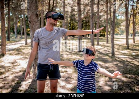 Junger Mann und Junge haben Spaß mit Virtual Reality-Headset Im Freien im Park Stockfoto