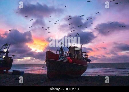 Hastings, East Sussex, Großbritannien. Dezember 2020. Möwen wirbeln im Morgengrauen über Hastings Fischerbooten mit einem bunten Sonnenaufgang über dem Ärmelkanal, am Tag der Gespräche von Boris Johnson mit EU-Kommissionspräsident Ursula von der Leyen, Versuchen, die Blockade der Fischereirechte in britischen Gewässern zu überwinden und ein Handelsabkommen in letzter Minute zu erreichen. Carolyn Clarke/Alamy Live News. Wintersonnenaufgang Stockfoto