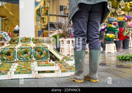 Kidderminster, Großbritannien. Dezember 2020. Am ersten Weihnachts-Shopping-Wochenende nach Lockdown zwei Einschränkungen aufgehoben werden sieht frühmorgens Markt Händler ihre Stände für das, was sie hoffen, wird ein geschäftiger festlicher Handelstag. Da die Käufer erwartet werden, dass sie in Kraft sind, sind öffentliche Warnschilder in der Stadt vorhanden, die die Menschen an wesentliche soziale Distanzierungsmaßnahmen erinnern. Eine Frau (unterer Abschnitt), die Gummistiefel trägt, hält an, um die Yuletide-Kränze zum Verkauf zu betrachten. Kredit: Lee Hudson/Alamy Live Nachrichten Stockfoto