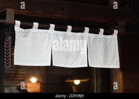 Der Vorhang-ähnliche Stoff, der vor traditionellen japanischen Restaurants und Geschäften hängt, dient nicht nur als Schild, sondern hat eine größere Bedeutung, Stockfoto