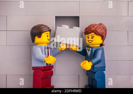 Tambow, Russische Föderation - 07. Juni 2020 Lego Geschäftsmann und Geschäftsfrau mit grauen Ziegel bereit, die Fertigstellung der Gebäudewand Stockfoto