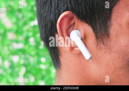 Junger Mann, der schnurloses Telefon aus nächster Nähe hören kann Stockfoto