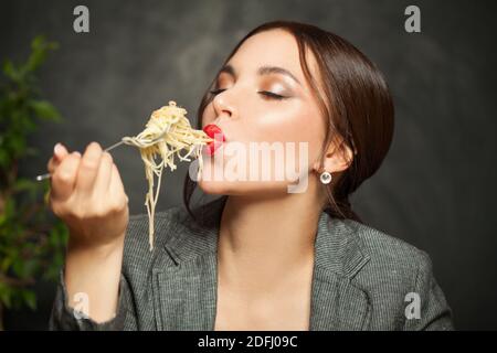 Glückliche Frau essen italienische Pasta Spaghetti auf schwarzem Hintergrund Stockfoto