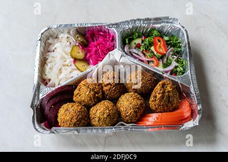 Gesunde Ernährung Lieferung im Restaurant Falafel mit Salat. Die Platte im Folienkastengehäuse entfernen. Traditionelles Essen. Stockfoto