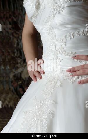 Nahaufnahme Brautkleid mit einem wunderschön gestickten Muster und Hände Auf der Taille mit einer schönen Maniküre Stockfoto