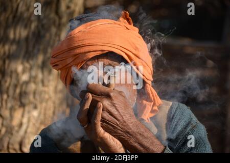 TIKAMGARH, MADHYA PRADESH, INDIEN - 03. DEZEMBER 2020: Indischer alter Mann, der chilam raucht. Stockfoto