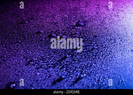 Farbenfroher abstrakter Hintergrund mit Wassertropfen, beleuchtet mit blauem und rosafarbtem LED-Licht. Stockfoto