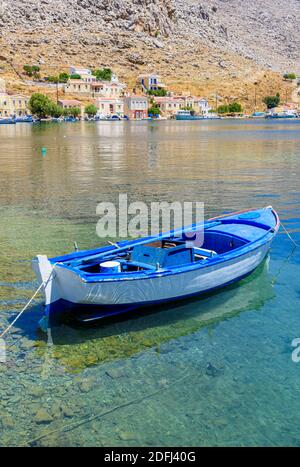 Kleines blaues Holzboot in den ruhigen Gewässern der Pedi Bay, Symi Island, Dodekanes, Griechenland Stockfoto