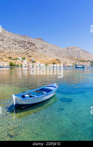 Kleines blaues Holzboot in den ruhigen Gewässern der Pedi Bay, Symi Island, Dodekanes, Griechenland Stockfoto