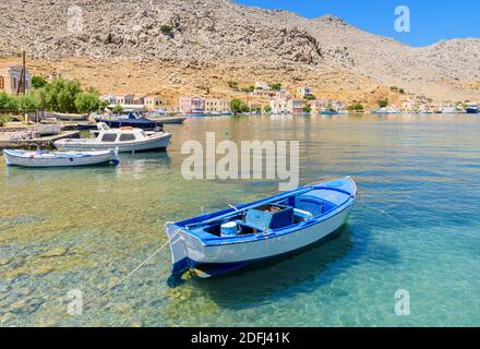 Kleines blaues Holzboot in den ruhigen Gewässern der Pedi Bay, Symi Island, Dodekanes, Griechenland Stockfoto