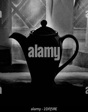 Portrait Schwarz-Weiß-Bild von Kaffeekanne gegen Vorhänge Stockfoto