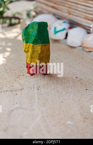 Ein Stein auf einem Sandstrand in Ghana Farben grün, gelb und rot als eine schöne Dekoration in der Natur gemalt Stockfoto