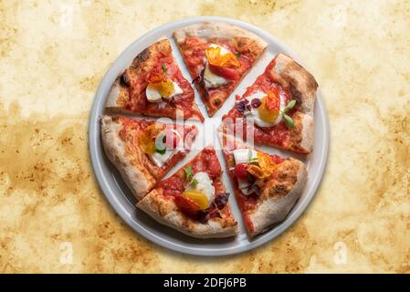 Gourmet-Pizza mit Tomate, Mozzarella, Basilikum und knuspriger Pfefferhaut. Sechs Scheiben in weißer Platte in der Draufsicht auf gelbem Marmor Hintergrund Stockfoto