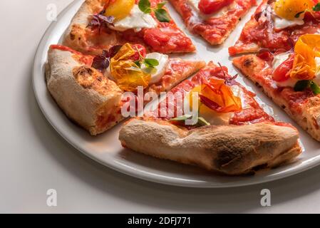 Nahaufnahme von Gourmet-Pizzascheiben mit Tomate, Mozzarella, Basilikum und knackiger Pfefferhaut. Verzehrfertige Pizza Stockfoto