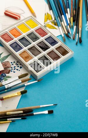 Aquarellfarben und Pinsel. Arbeitsplatz und Schreibtisch des Künstlers. Farbpalette. Hintergrund wird gezeichnet. Ort für Ihren Text. Stockfoto