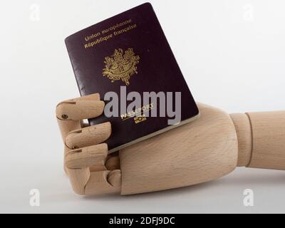 Eine hölzerne Hand mit einem französischen Pass. Konzept für Reisen und Einwanderung. Stockfoto