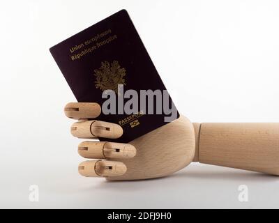 Eine hölzerne Hand mit einem französischen Pass. Konzept für Reisen und Einwanderung. Stockfoto