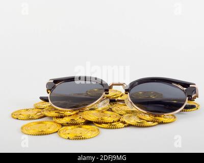 Eine Sonnenbrille auf einem Haufen Goldmünzen. Konzept für Geld und Urlaub. Stockfoto