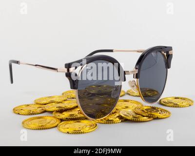 Eine Sonnenbrille auf einem Haufen Goldmünzen. Konzept für Geld und Urlaub. Stockfoto