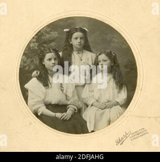 Original Edwardian montierte Fotografie von 2 Schwestern und einem Cousin, im Teenageralter, Ruby, Peggy und Dora, um 1905, Hamilton bei Glasgow, South Lanarkshire, Schottland, Großbritannien Stockfoto