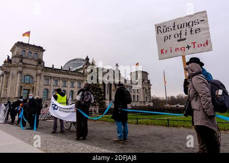 Deutschland, Berlin, 05. Dezember 2020: Demonstranten bilden vor dem Reichstag eine Menschenkette, um im Rahmen der anstehenden Haushaltsdiskussionen im Deutschen Bundestag nächste Woche gegen die Erhöhung der Rüstungsausgaben zu protestieren. Die Organisatoren der Friedensinitiative "Abrüstung statt Aufrüstung" fordern beim bundesweiten Tag für "Abrüstung und eine neue Politik der Entspannung" eine Kürzung der deutschen Rüstungsexporte und einen sozial- und umweltpolitischen Wandel. (Foto von Jan Scheunert/Sipa USA) Stockfoto