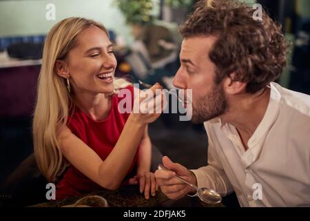 Ein junges Mädchen füttert seinen Freund bei Valentinstag Feier in einem Restaurant in einer entspannten Atmosphäre. Zusammen, Valentinstag, Feier Stockfoto