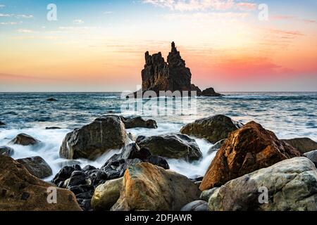 Sonnenuntergang am Strand mit Wellen und Felseninsel in der Meer auf teneriffa Stockfoto