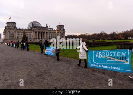 Berlin, Berlin, Deutschland. Dezember 2020. Demonstranten bilden vor dem Reichstag eine Menschenkette, um im Rahmen der anstehenden Haushaltsdiskussionen im Deutschen Bundestag nächste Woche gegen die Erhöhung der Rüstungsausgaben zu protestieren. Die Organisatoren der Friedensinitiative "Abrüstung statt Aufrüstung" fordern beim bundesweiten Tag für "Abrüstung und eine neue Politik der Entspannung" eine Kürzung der deutschen Rüstungsexporte und einen sozial- und umweltpolitischen Wandel. Quelle: Jan Scheunert/ZUMA Wire/Alamy Live News Stockfoto