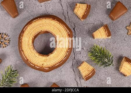 Rundes Stück traditioneller deutscher Winterkuchen mit Schichtenüberbacken, genannt „Baumkuchen“ Glasiert mit Schokolade mit dünnen Schichten innerhalb des Kuchens Stockfoto