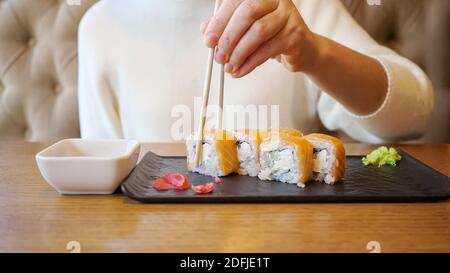 Junge, unkenntliche Frau, die in einem Café Brötchen mit Lachs isst. Stockfoto