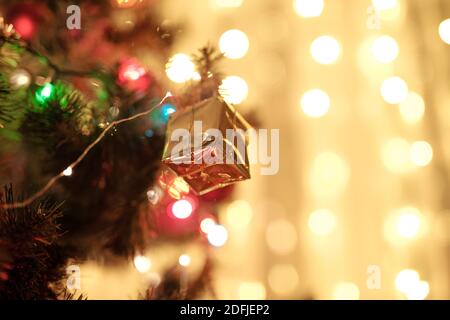 Niedliche Dekoration für Weihnachtsbaum in Form von kleinen geschenkbox In goldenes Papier gewickelt und mit dünnem Faden gebunden Auf Nadelzweig Stockfoto