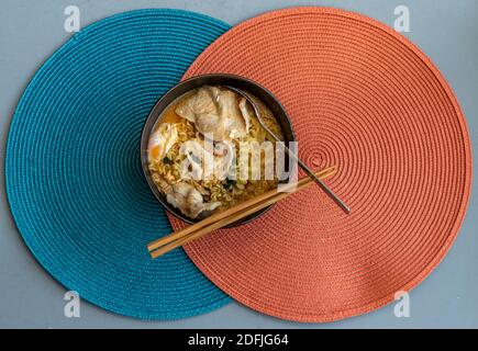 Eiernudeln mit Schweinefleisch, Spiegelei, Gemüse und Suppen in Schüssel und Essstäbchen mit Löffel kochen. Thailändische Nudelsuppe, selektiver Fokus. Stockfoto