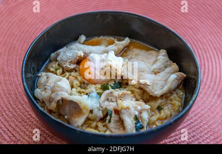 Eiernudeln mit Schweinefleisch, Spiegelei, Gemüse und Suppen in einer Schüssel kochen. Thailändische Nudelsuppe, selektiver Fokus. Stockfoto
