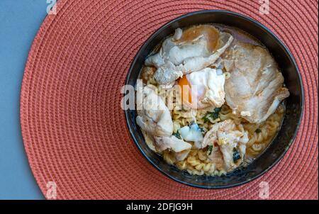 Eiernudeln mit Schweinefleisch, Spiegelei, Gemüse und Suppen in einer Schüssel kochen. Thailändische Nudelsuppe, selektiver Fokus. Stockfoto