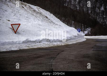Verschneite Straße zwischen Bergen, Autofahren und gefährlicher Natur und Landschaft Stockfoto