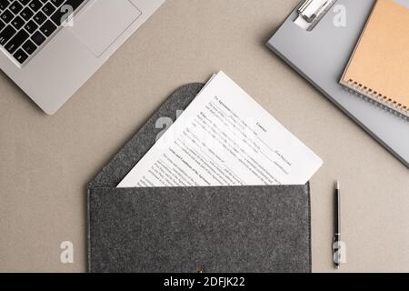 Überblick über den Finanzvertrag in großem grauen Umschlag umgeben von Laptop, Ordner mit Zwischenablage mit Dokumenten und Copybook am Arbeitsplatz Stockfoto