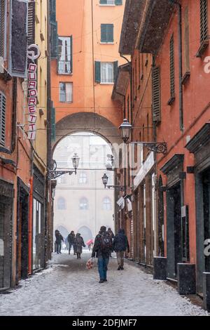 Schnee fällt in der Via Clavature mit Blick durch den Bogen zum Palazzo Comunale auf der Piazza Maggiore, Bologna, Italien Stockfoto