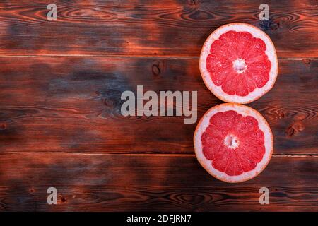 Zwei Hälften reifer roter Grefruit auf einem hölzernen Hintergrund. Platz für Text Stockfoto