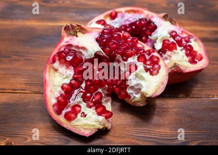 Heller saftiger Fruchtgranatapfel, der auf einem hölzernen Hintergrund geöffnet wurde Stockfoto