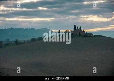 Landschaft mit landwirtschaftlichen Feldern, Hügeln und Wolken in der Toskana, Italien im Herbst bei Sonnenaufgang. Stockfoto