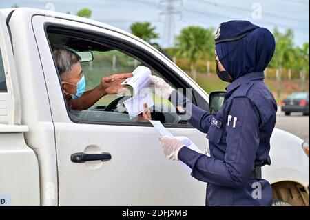 Selangor, Malaysia. Dezember 2020. Ein Polizist überprüft ein Fahrzeug an einem Kontrollpunkt auf einer Autobahn in Setia Alam des Staates Selangor, Malaysia, 5. Dezember 2020. Die malaysische Regierung sagte am Samstag, dass sie die Bewegungskontrollordnung in mehreren Bereichen bis zum 20. Dezember verlängern wird, um die Ausbreitung von COVID-19 zu kontrollieren. Am Samstag meldete das malaysische Gesundheitsministerium 1,123 neue bestätigte COVID-19 Fälle, womit die nationale Gesamtzahl auf 71,359 angesetzt wurde. Quelle: Chong Voon Chung/Xinhua/Alamy Live News Stockfoto