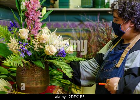 Der Besitzer eines Blumenladens, der an einem Blumenstrauß arbeitet Von Blumen nach der Wiedereröffnung durch covid Stockfoto